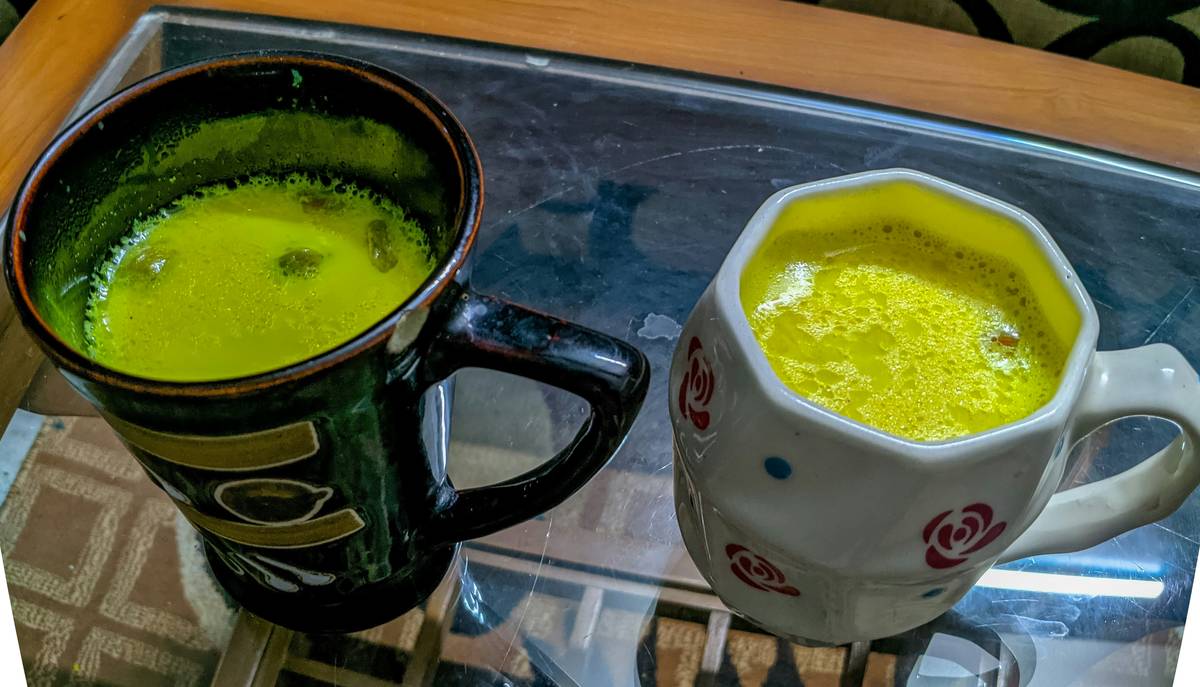 Woman drinking golden milk for anxiety while journaling at sunset